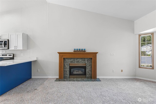 unfurnished living room with lofted ceiling, baseboards, carpet flooring, and a tile fireplace