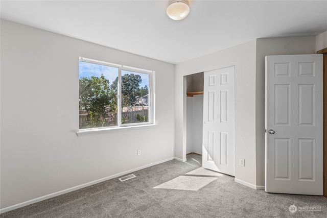 unfurnished bedroom featuring light carpet and a closet