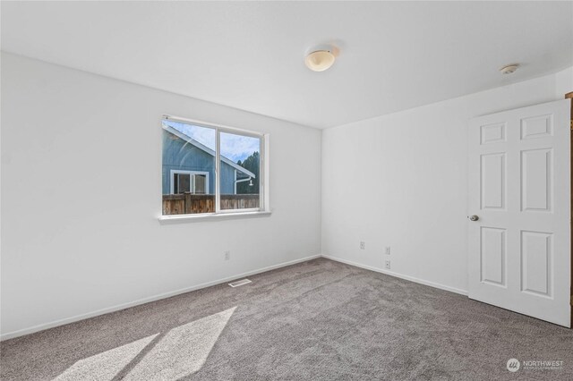 empty room featuring carpet, visible vents, and baseboards