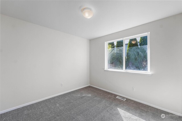 carpeted spare room featuring visible vents and baseboards