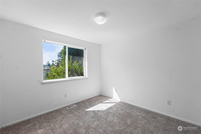 unfurnished room with carpet flooring, visible vents, and baseboards