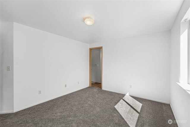 carpeted spare room featuring baseboards