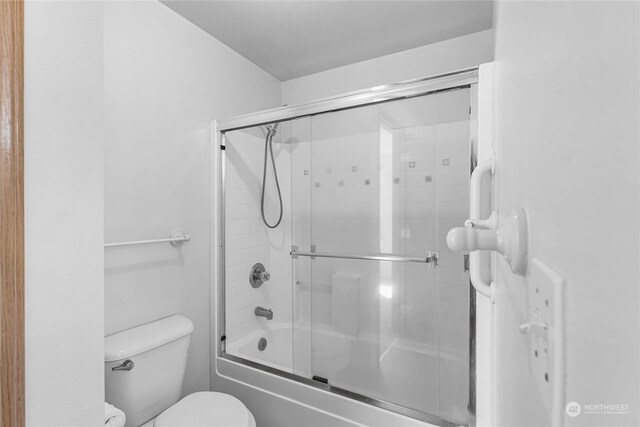 full bath featuring bath / shower combo with glass door and toilet