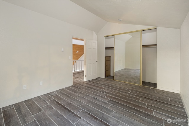 unfurnished bedroom with dark wood-type flooring, a closet, and lofted ceiling