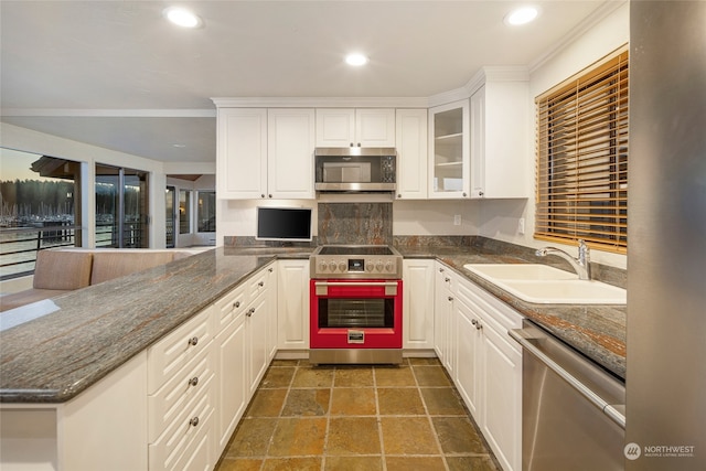 kitchen with dark stone counters, kitchen peninsula, sink, appliances with stainless steel finishes, and white cabinets