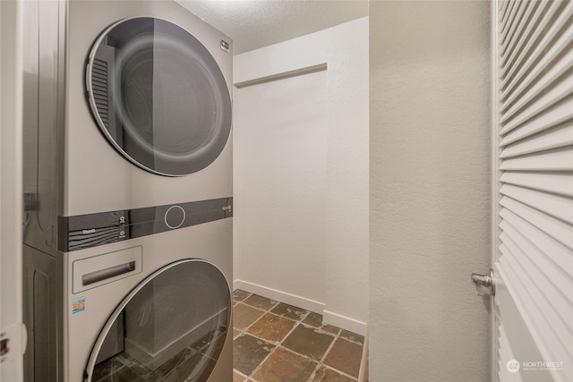 laundry room featuring a textured ceiling and stacked washer / drying machine