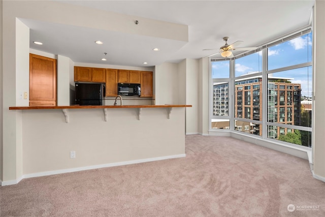 kitchen featuring plenty of natural light, black appliances, kitchen peninsula, and a kitchen breakfast bar