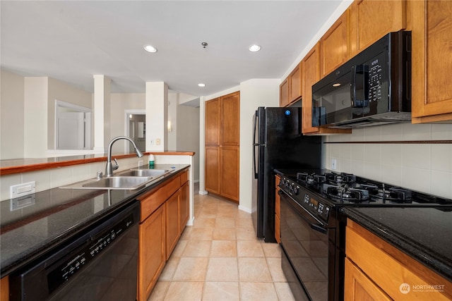 kitchen with dark stone countertops, black appliances, tasteful backsplash, and sink