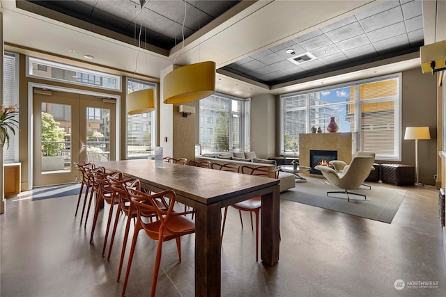 dining area featuring a raised ceiling, concrete floors, and french doors