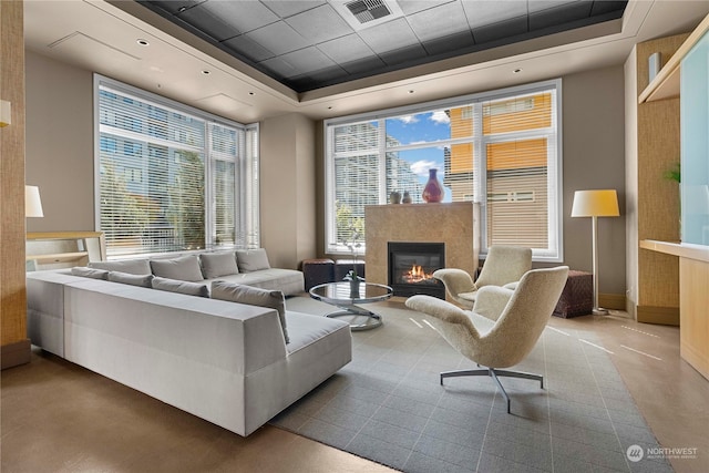 living room with a tray ceiling, plenty of natural light, and concrete floors