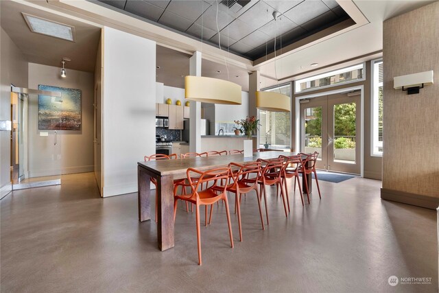 dining area featuring a raised ceiling, concrete floors, and french doors