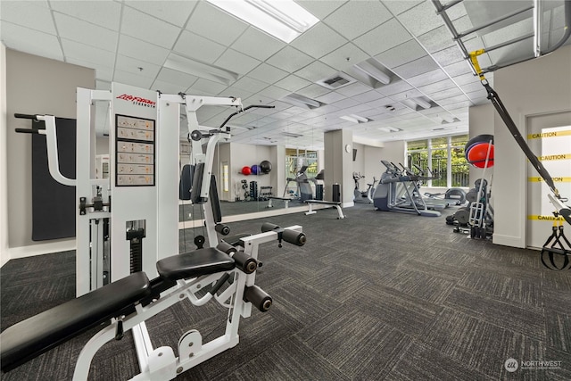 workout area featuring dark colored carpet and a drop ceiling