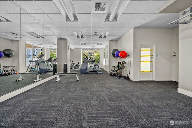 exercise room with a healthy amount of sunlight, dark carpet, and a drop ceiling