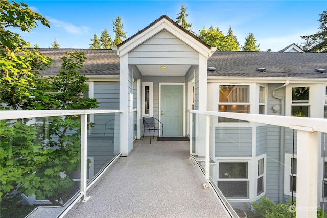 view of exterior entry with a shingled roof