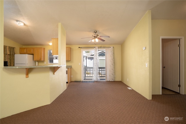 kitchen with white fridge, dark colored carpet, a breakfast bar area, and ceiling fan