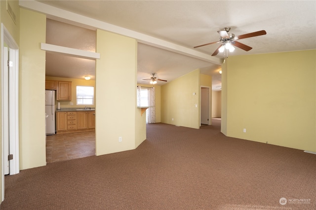 unfurnished living room with dark carpet, sink, and ceiling fan