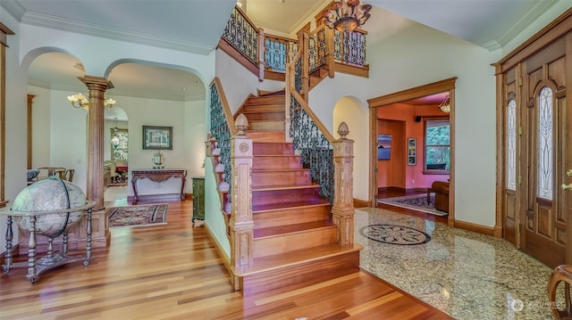 foyer entrance with hardwood / wood-style floors, crown molding, and ornate columns