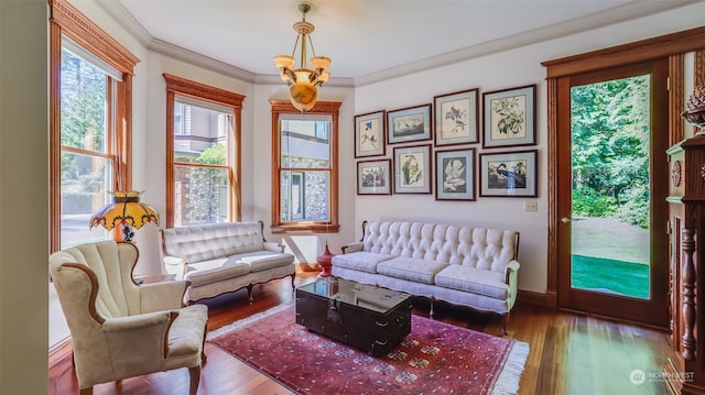 living room with ornamental molding, hardwood / wood-style floors, and an inviting chandelier