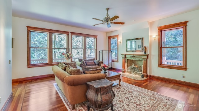 living room featuring a high end fireplace, hardwood / wood-style flooring, and ceiling fan