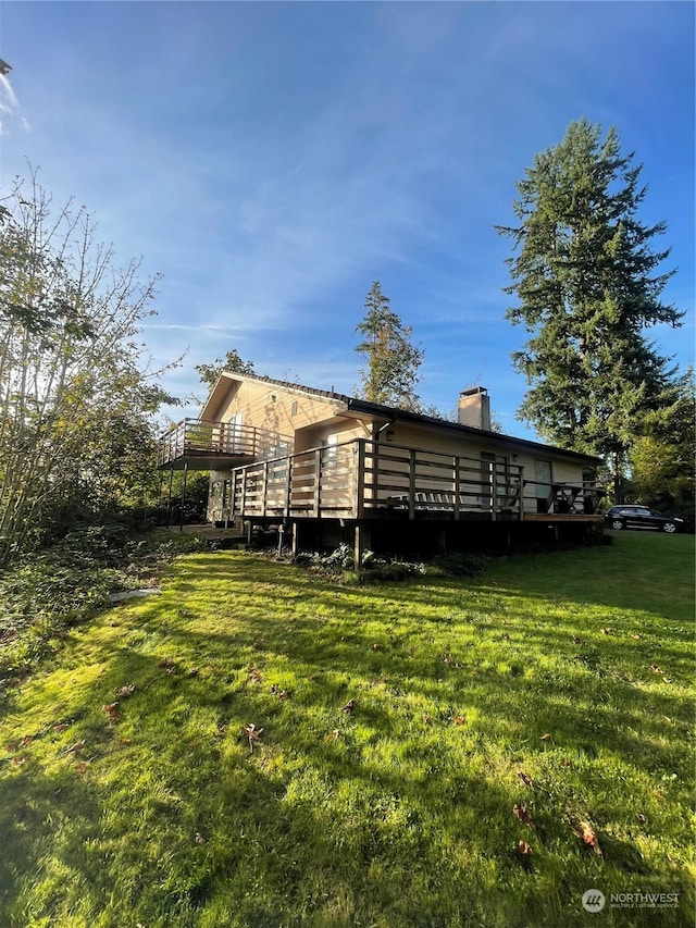 rear view of house featuring a wooden deck and a lawn