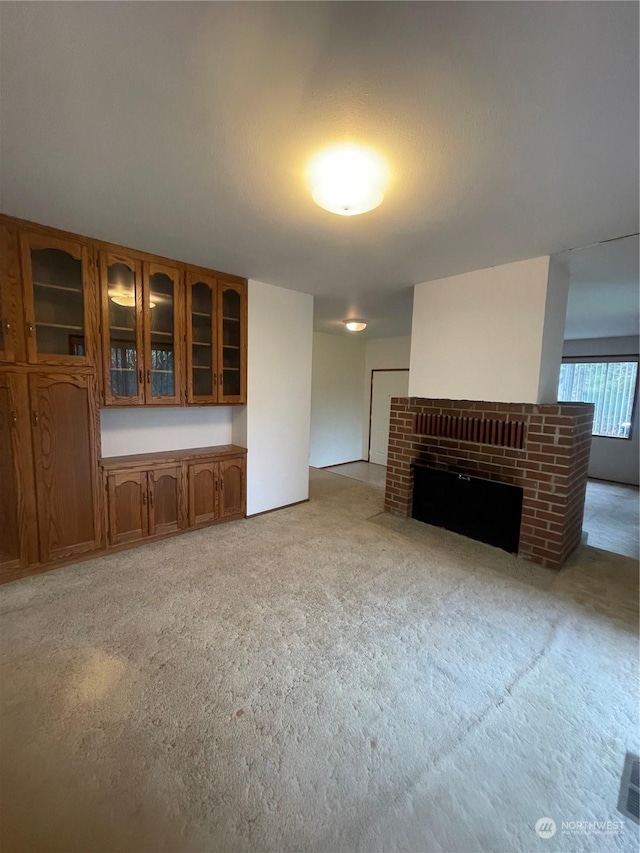 unfurnished living room with a brick fireplace and light colored carpet