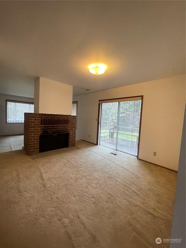 unfurnished living room featuring a brick fireplace and carpet flooring