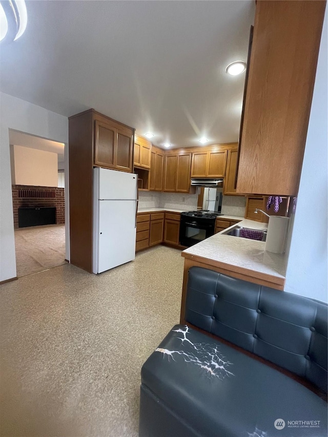 kitchen featuring sink, white refrigerator, a fireplace, black range oven, and kitchen peninsula