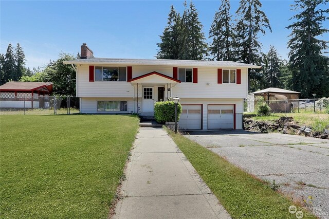 raised ranch featuring a garage and a front yard