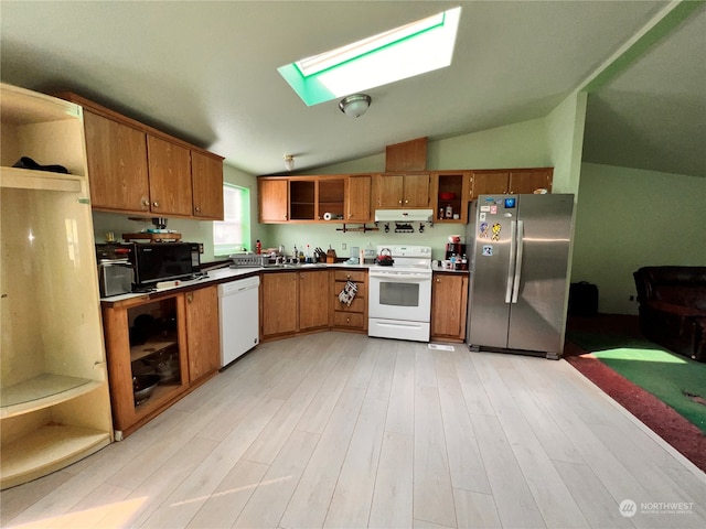 kitchen with vaulted ceiling with skylight, sink, white appliances, and light hardwood / wood-style floors