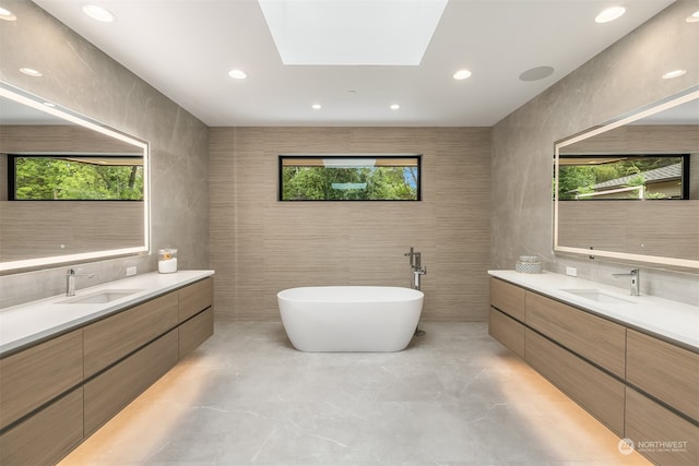 bathroom featuring a tub to relax in, vanity, plenty of natural light, and a skylight