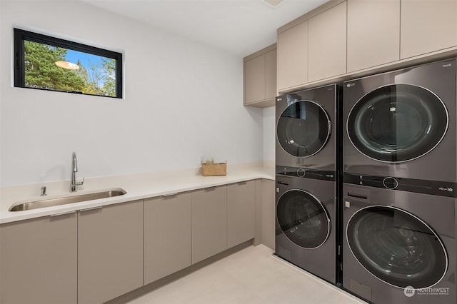 laundry area featuring cabinets, sink, and stacked washer / dryer