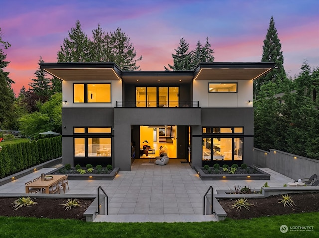 back house at dusk with a patio area