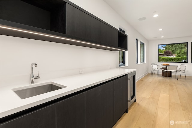 kitchen with light wood-type flooring, beverage cooler, and sink