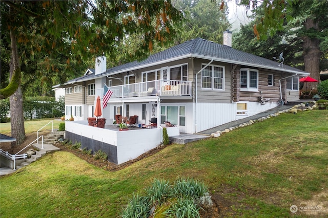 rear view of house featuring a lawn, a patio, and a balcony