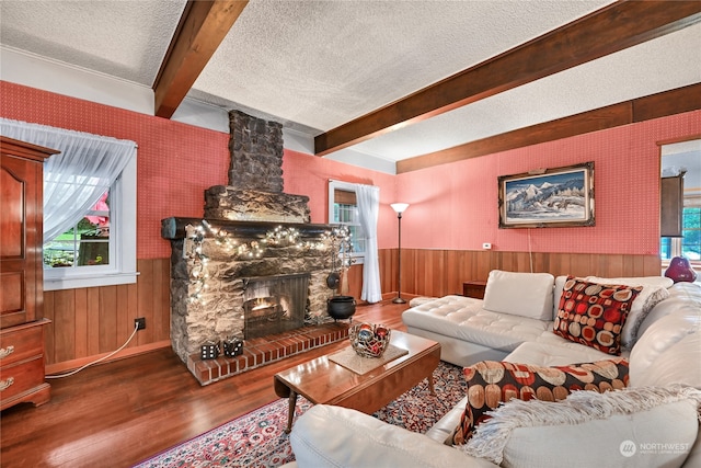 living room featuring a textured ceiling, a healthy amount of sunlight, a stone fireplace, and hardwood / wood-style flooring