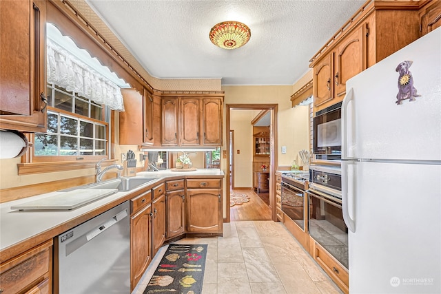 kitchen featuring appliances with stainless steel finishes, a textured ceiling, light hardwood / wood-style flooring, and sink