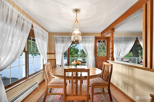 dining room featuring a baseboard heating unit, a wealth of natural light, hardwood / wood-style floors, and an inviting chandelier