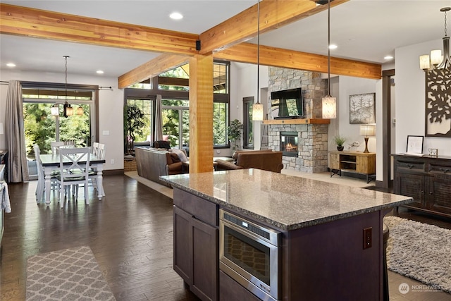 73 Sweet Shop Ln, Cle Elum, WA 98922 - kitchen featuring dark wood finished floors, stainless steel microwave, open floor plan, a stone fireplace, and a notable chandelier