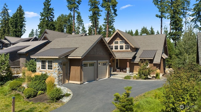 view of front facade featuring driveway, stone siding, a garage, and board and batten siding