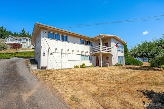 view of front of property featuring a balcony and a front yard