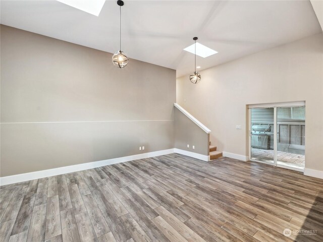 unfurnished living room with hardwood / wood-style floors and a skylight