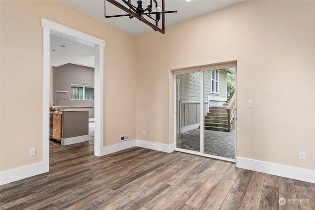 spare room featuring dark wood-type flooring and a notable chandelier