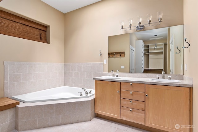 bathroom with tile patterned flooring, vanity, and tiled bath