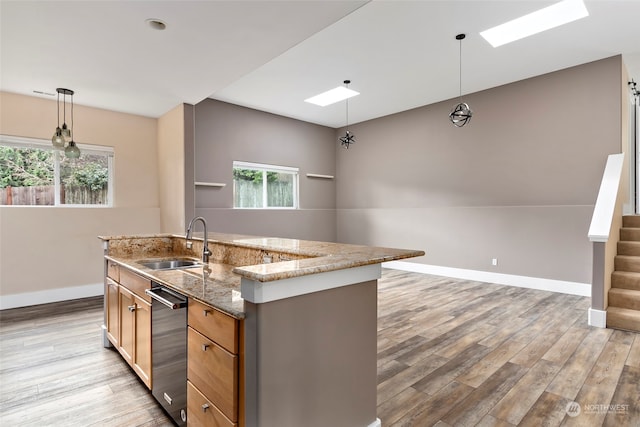 kitchen with a healthy amount of sunlight, a center island with sink, pendant lighting, and sink