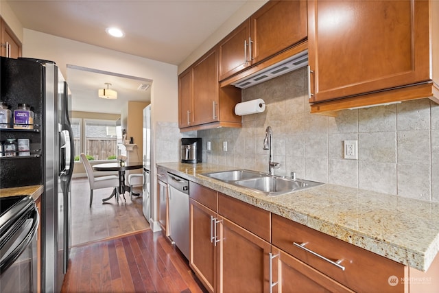 kitchen with dark wood-type flooring, decorative backsplash, stainless steel appliances, and sink