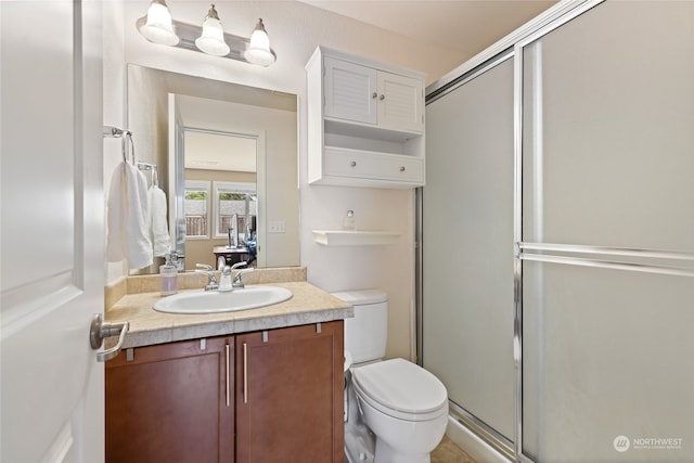 bathroom featuring vanity, toilet, and a shower with door