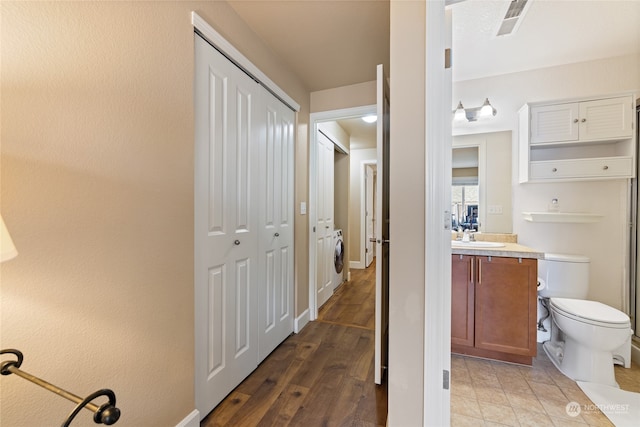 bathroom with wood-type flooring, washer and dryer, vanity, and toilet