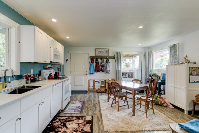 kitchen featuring a healthy amount of sunlight, light wood-type flooring, sink, and white appliances