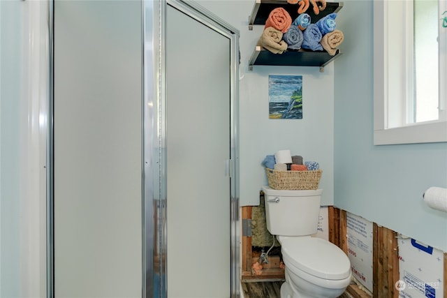 bathroom featuring a shower with door, toilet, and hardwood / wood-style flooring