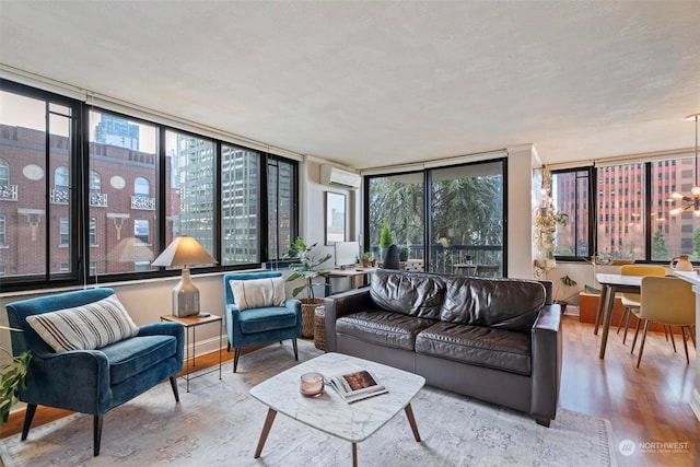 living room featuring a wall unit AC, wood-type flooring, and a wealth of natural light